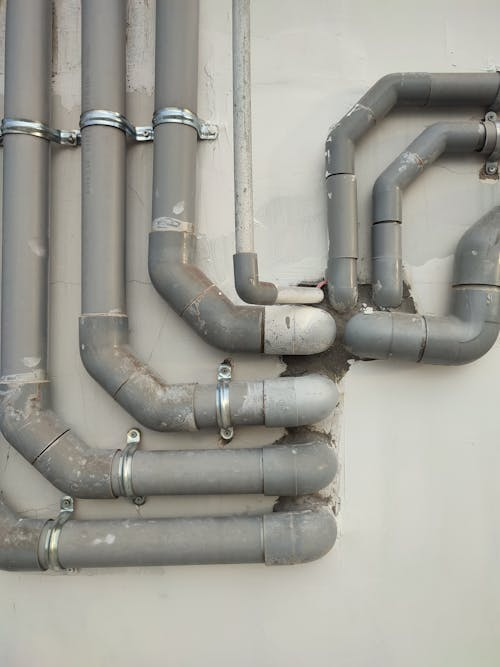 Industrial plumbing pipes mounted along the wall inside a commercial building.
