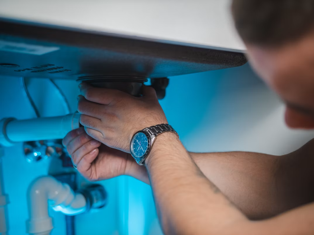 a man fixing a water heater pipe in a room